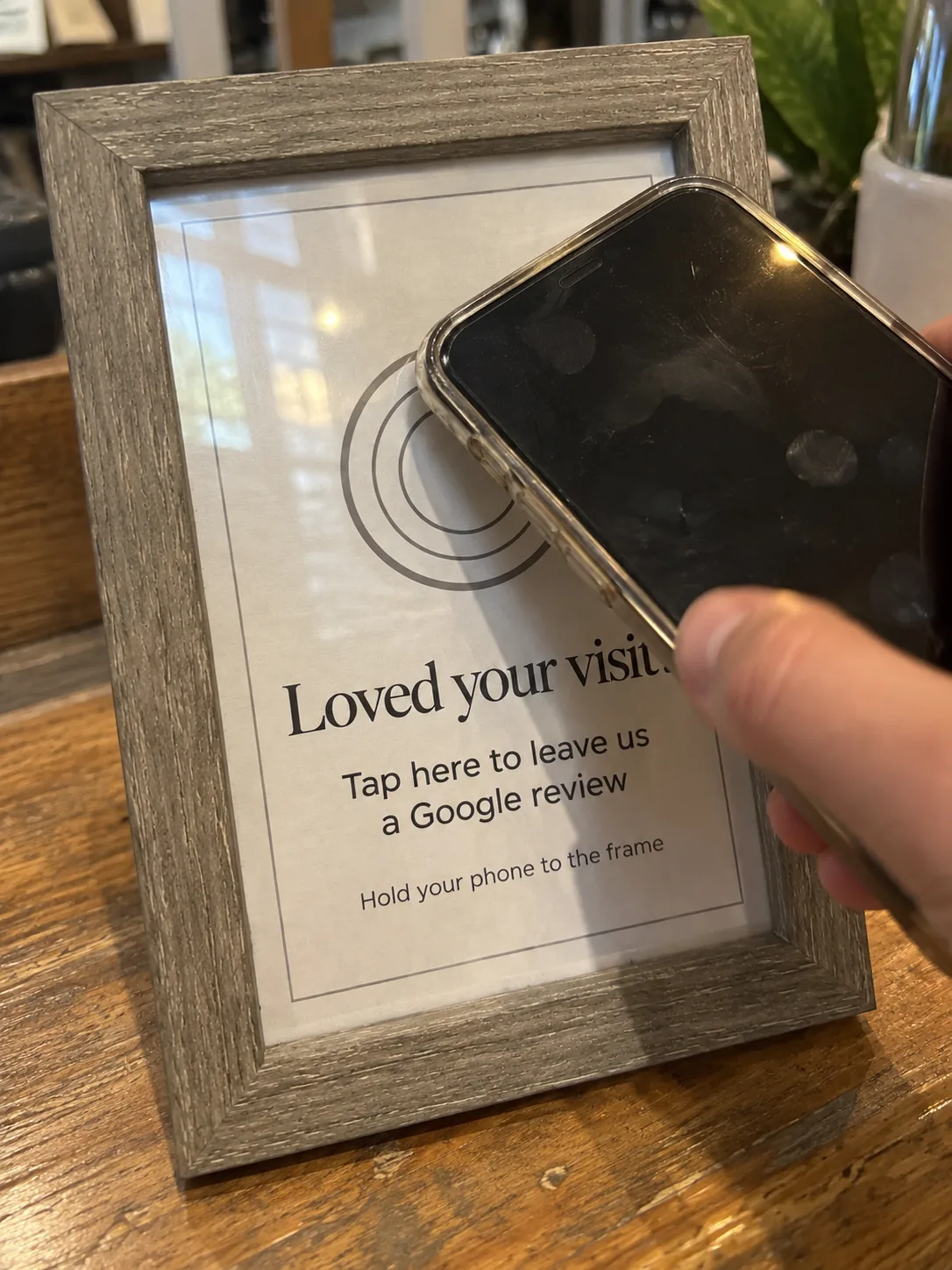 A phone held to the tap mark on the TapIt Frame